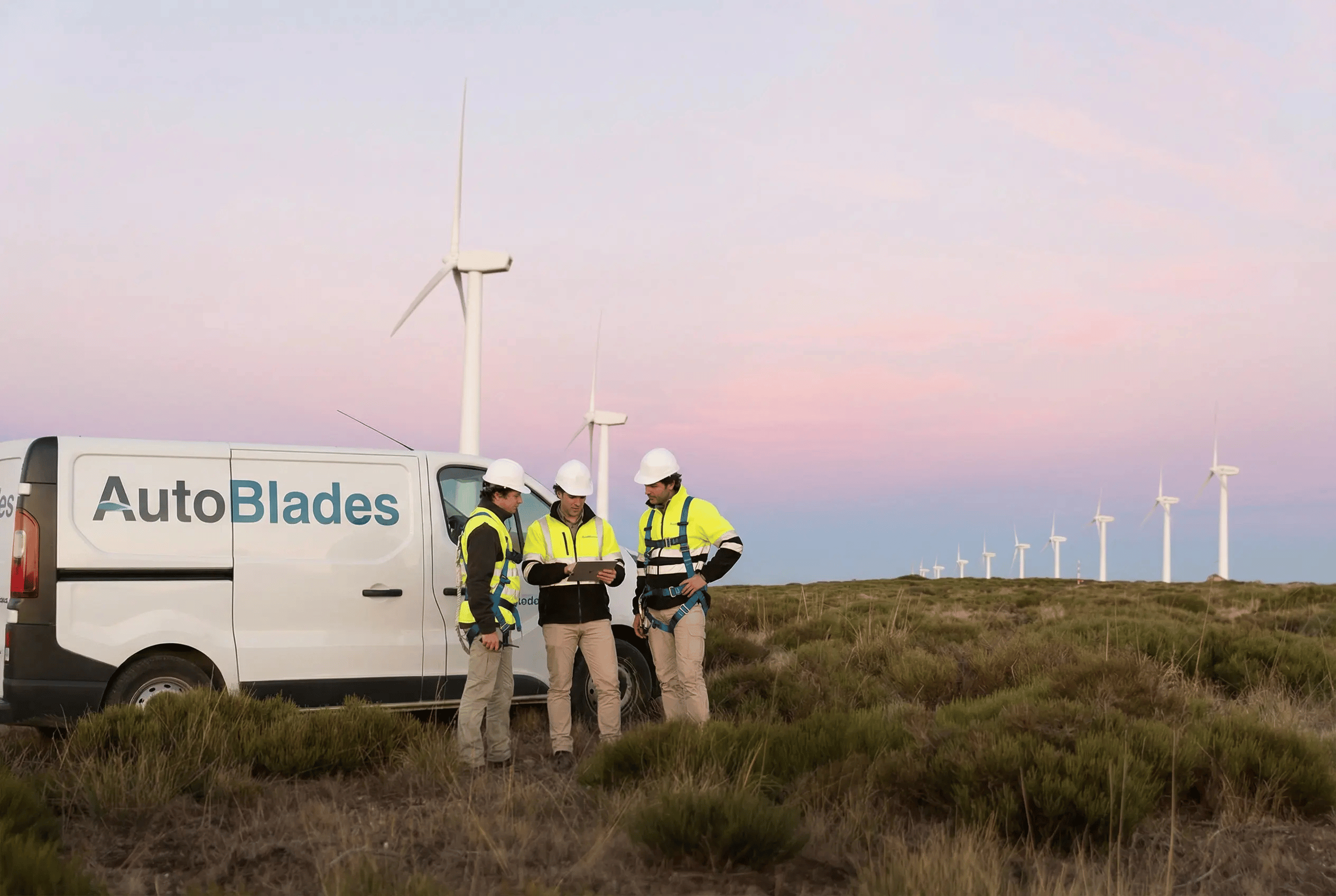 Wind turbine technicians reviewing work at a wind farm at sunset