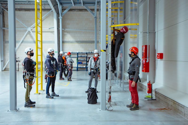 A group of technicians in harnesses and PPE during rope access training at a warehouse training facility